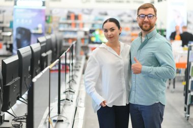 Teknoloji mağazasından alışveriş yapan genç bir çift. Evleri için yeni televizyon satın alıyorlar..