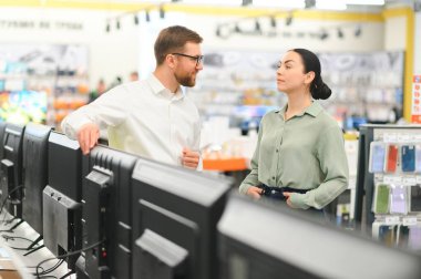 genç kadın tezgâhtar ev aletleri alışveriş merkezi süpermarket ile TV'nin seçimi.