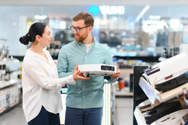 stock image The happy couple chooses wireless vacuum cleaner at store.