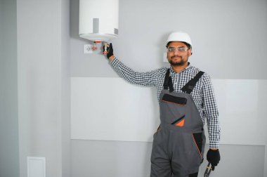 Hintli erkek tesisatçı banyoda ısıtıcıyı ayarlıyor..