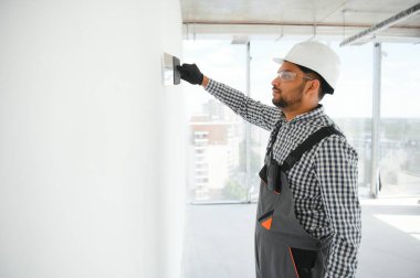 İşçi malayla duvarlara alçı saçıyor, tamirat yapıyor.