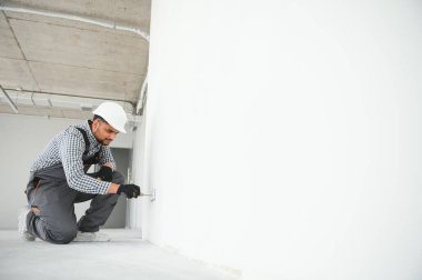 Hintli bir elektrikçi yeni bir binaya priz kuruyor..