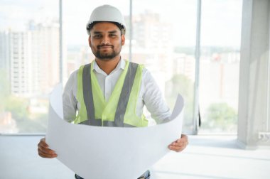 Hintli şantiye müdürü miğfer takıyor, inşaat alanında düşünüyor. Karışık ırk el işçisinin ya da mimarın portresi.