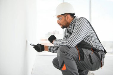 İşçi malayla duvarlara alçı saçıyor, tamirat yapıyor.