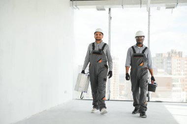 Çok ırklı bir grup inşaat inşaat işçisi iş yerinde toplanıyor..