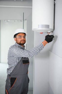 Hintli erkek tesisatçı banyoda ısıtıcıyı ayarlıyor..