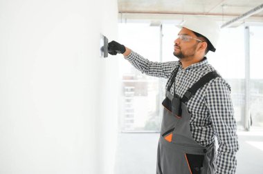 İşçi malayla duvarlara alçı saçıyor, tamirat yapıyor.