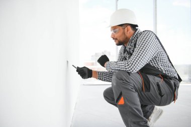 İşçi malayla duvarlara alçı saçıyor, tamirat yapıyor.