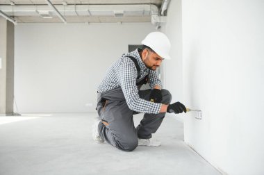 Hintli bir elektrikçi yeni bir binaya priz kuruyor..