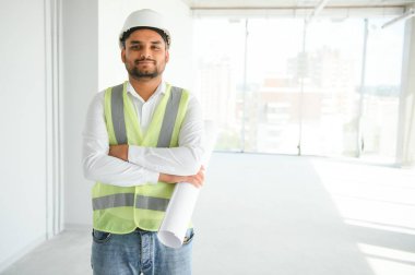 İnşaat alanında miğfer takan yakışıklı genç Hintli inşaat mühendisi ya da mimarın portresi..