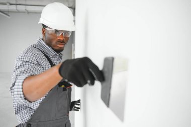 İş, inşaat ve insan konsepti. Kapalı alanda sıva aletleri olan Afrikalı mimar..