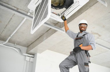 Afrikalı Amerikalı tamircinin klimayı tamir edişinin düşük açılı görüntüsü.