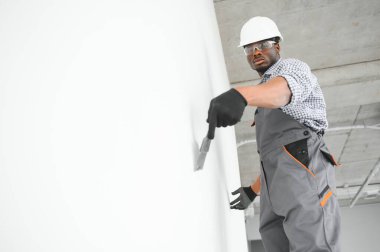 İş, inşaat ve insan konsepti. Kapalı alanda sıva aletleri olan Afrikalı mimar..