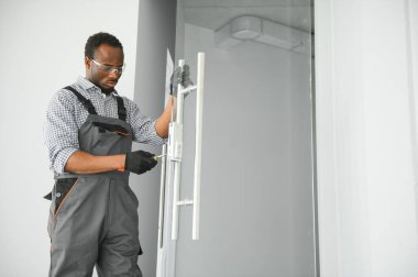 İşçi ofise cam kapı kuruyor.