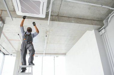 Profesyonel bir tamirci odaya klima kuruyor..