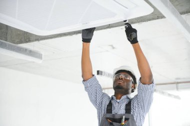 Afrikalı Amerikalı tamircinin klimayı tamir edişinin düşük açılı görüntüsü.