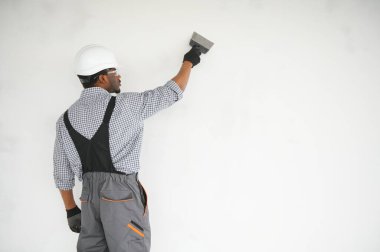 İş, inşaat ve insan konsepti. Kapalı alanda sıva aletleri olan Afrikalı mimar..