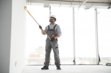 Boyacı duvarı boyuyor, boya silindiriyle..