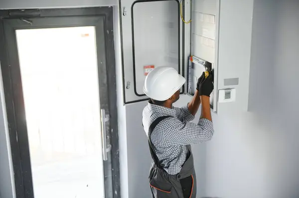 stock image A male electrician works in a switchboard.