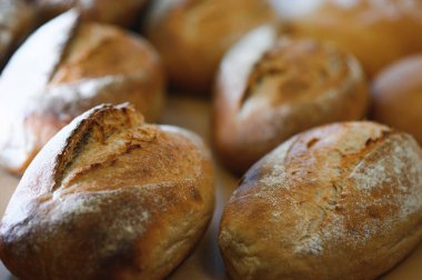 Yuvarlak ekmek yakın plan. Fırın raflarında altın hamurlu taze ekşi ekmek. Lezzetli ekmekle birlikte fırın içeriği. Hamur işleri.