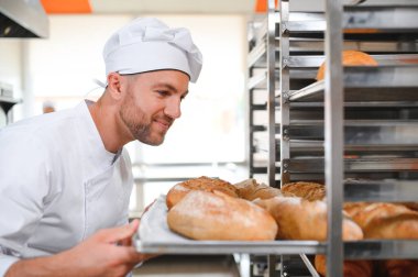 Erkek baker bir tepsi fırında ekmek fırını dükkanında holding.