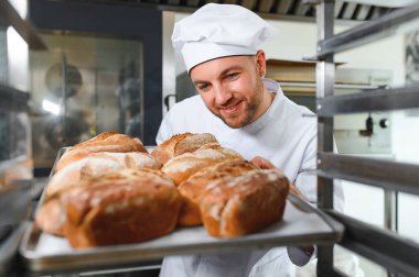 Erkek baker bir tepsi fırında ekmek fırını dükkanında holding.