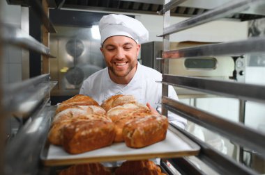 Mutlu fırıncı fırında ekmek ile tepsi nin yanında duran.