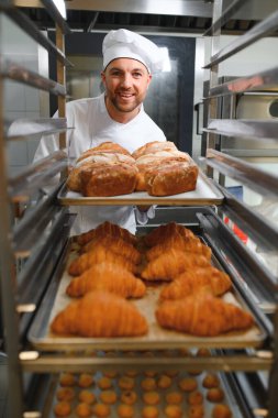 Erkek baker bir tepsi fırında ekmek fırını dükkanında holding.