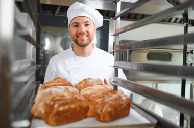 Erkek baker bir tepsi fırında ekmek fırını dükkanında holding.