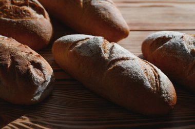 Fırın raflarında taze pişmiş ekmek. Parlak ışıkta ekmek çeşitliliği. Tahta raflarda altın hamurlu ekmek. Ekmek çeşitleri..