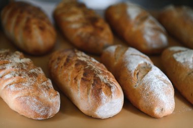 Yuvarlak ekmek yakın plan. Fırın raflarında altın hamurlu taze ekşi ekmek. Lezzetli ekmekle birlikte fırın içeriği. Hamur işleri.