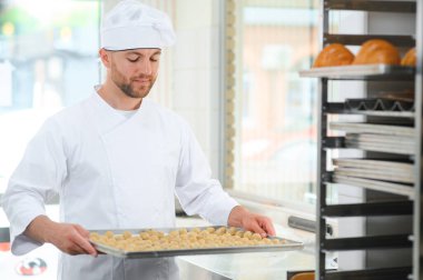 İş yerindeki genç beyaz işçi kurabiye tepsisi takıyor..