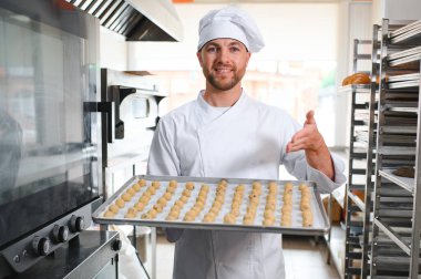 İş yerindeki genç beyaz işçi kurabiye tepsisi takıyor..