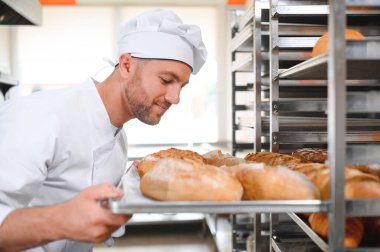 Erkek baker bir tepsi fırında ekmek fırını dükkanında holding.