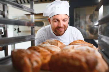 Erkek baker bir tepsi fırında ekmek fırını dükkanında holding.