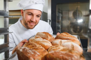 Mutlu fırıncı fırında ekmek ile tepsi nin yanında duran.