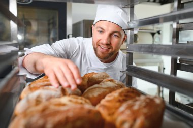 Mutlu fırıncı fırında ekmek ile tepsi nin yanında duran.