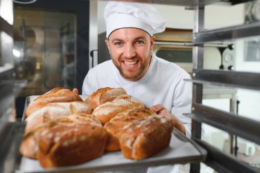 Erkek baker bir tepsi fırında ekmek fırını dükkanında holding.