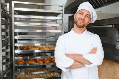 Yakışıklı baker ekmek ekmek ve fırın arka planda portresi.