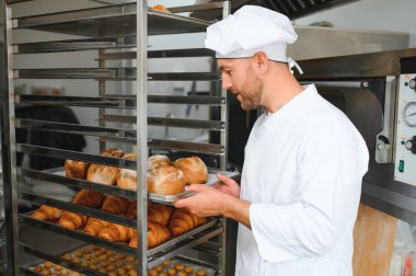 Erkek baker bir tepsi fırında ekmek fırını dükkanında holding.