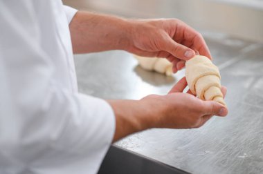 Erkek bir fırıncı fırın mutfağında kruvasan yapıyor..