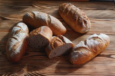 Fırın raflarında taze pişmiş ekmek. Parlak ışıkta ekmek çeşitliliği. Tahta raflarda altın hamurlu ekmek. Ekmek çeşitleri..