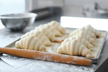 Pişirme tepsisinde çiğ kruvasan, pişirme için hazır..