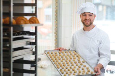 İş yerindeki genç beyaz işçi kurabiye tepsisi takıyor..