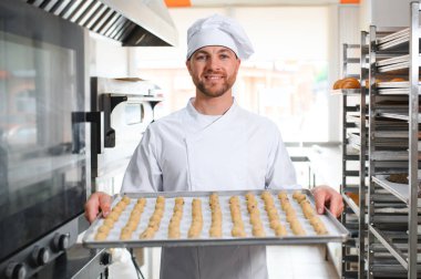 İş yerindeki genç beyaz işçi kurabiye tepsisi takıyor..