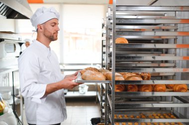 Erkek baker bir tepsi fırında ekmek fırını dükkanında holding.