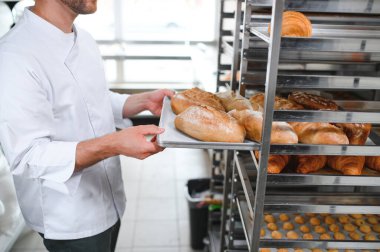 Erkek baker bir tepsi fırında ekmek fırını dükkanında holding.