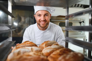Erkek baker bir tepsi fırında ekmek fırını dükkanında holding.