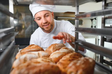 Erkek baker bir tepsi fırında ekmek fırını dükkanında holding.