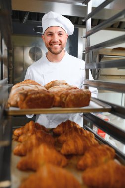 Mutlu fırıncı fırında ekmek ile tepsi nin yanında duran.